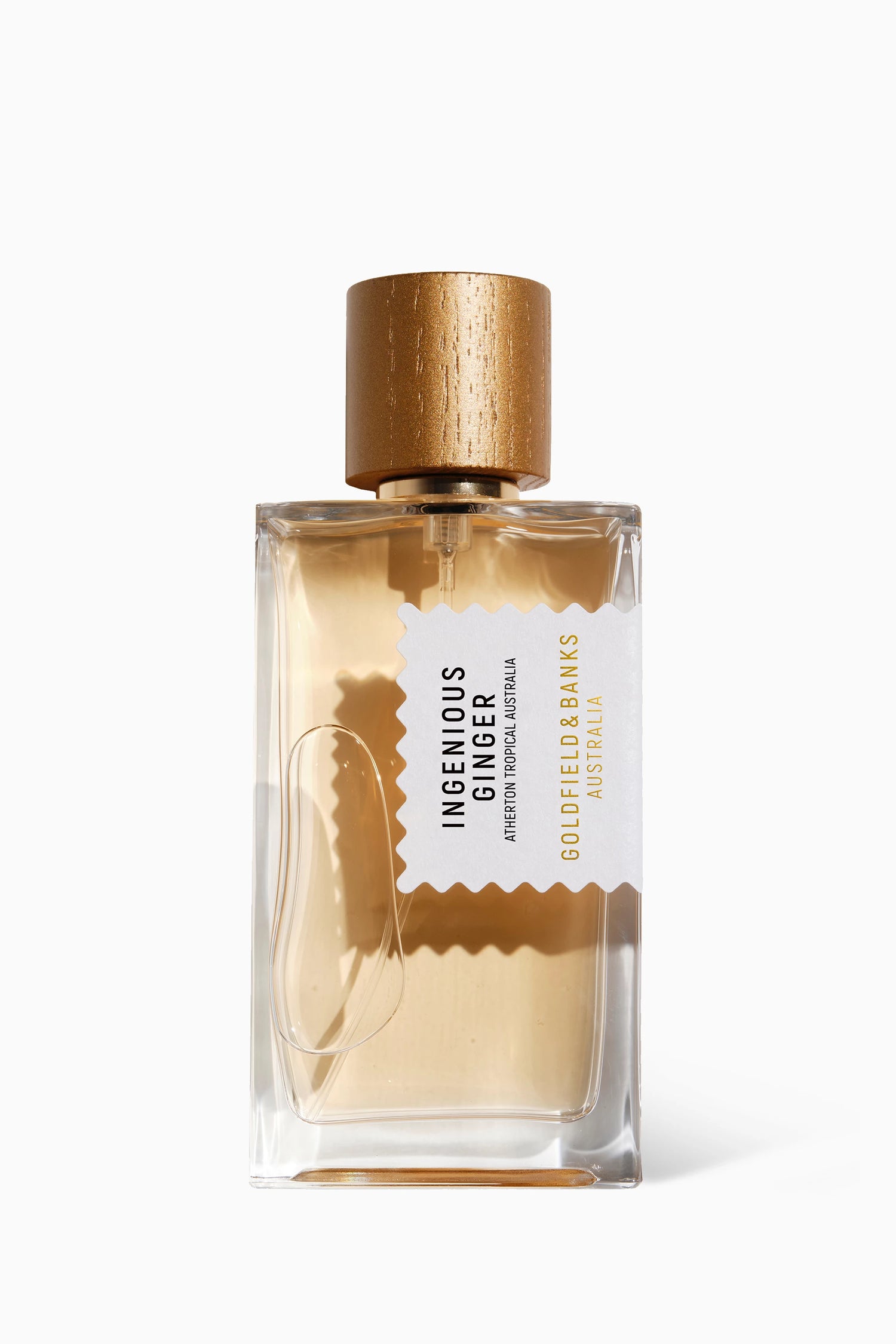 A bottle of 'Ingenious Ginger by Goldfield & Banks' perfume with a clear label, showcasing the amber-colored liquid inside. The perfume bottle has a wooden cap and is displayed against a white background.