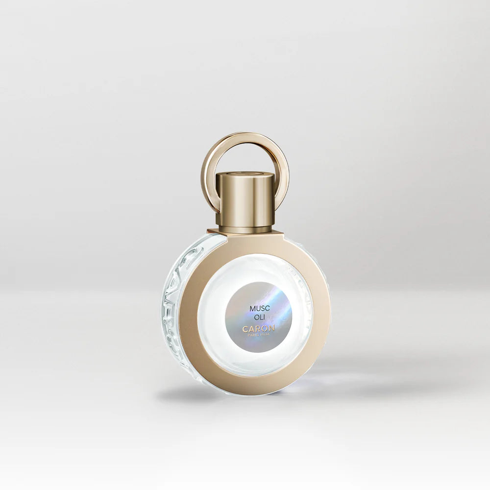 Musc Oli by Caron. Perfume bottle with gold cap on a light gray background