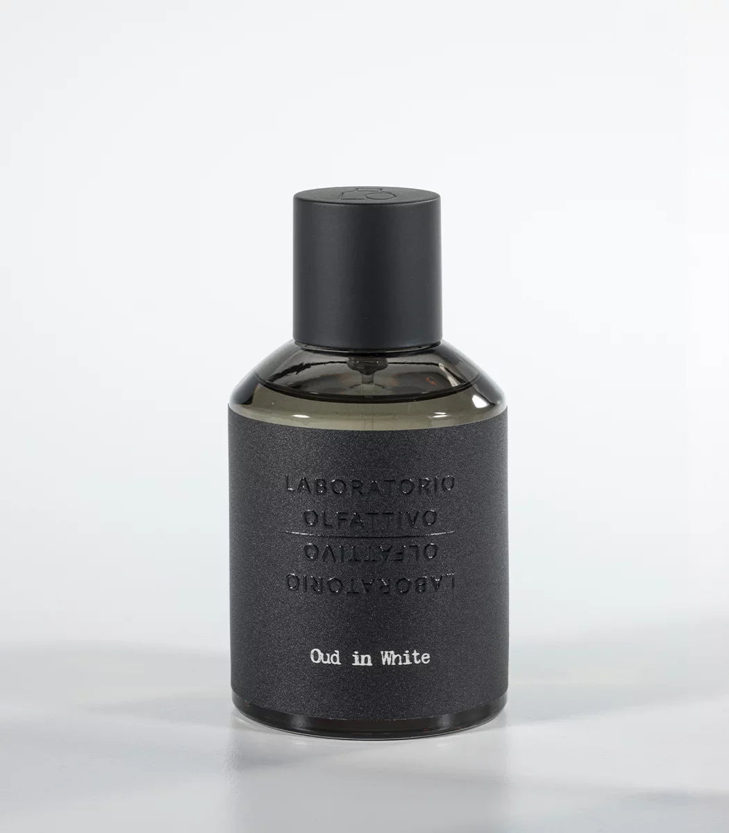 A bottle of 'Oud in White by Laboratorio Olfattivo 100ml' perfume with a dark cap and label, set against a plain background.