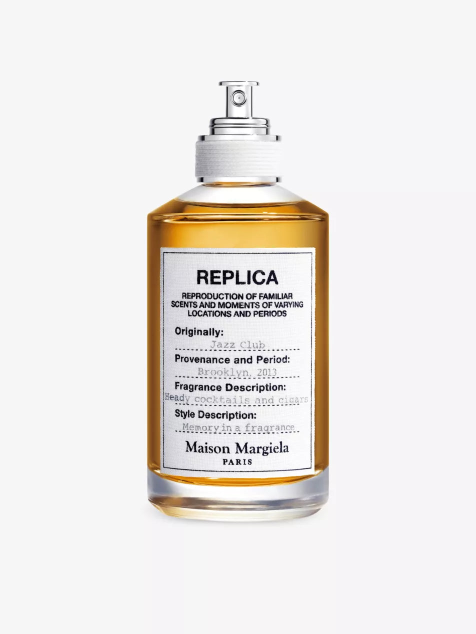 A bottle of Replica Jazz Club perfume by Maison Margiela with a white label and the brand's name on it.