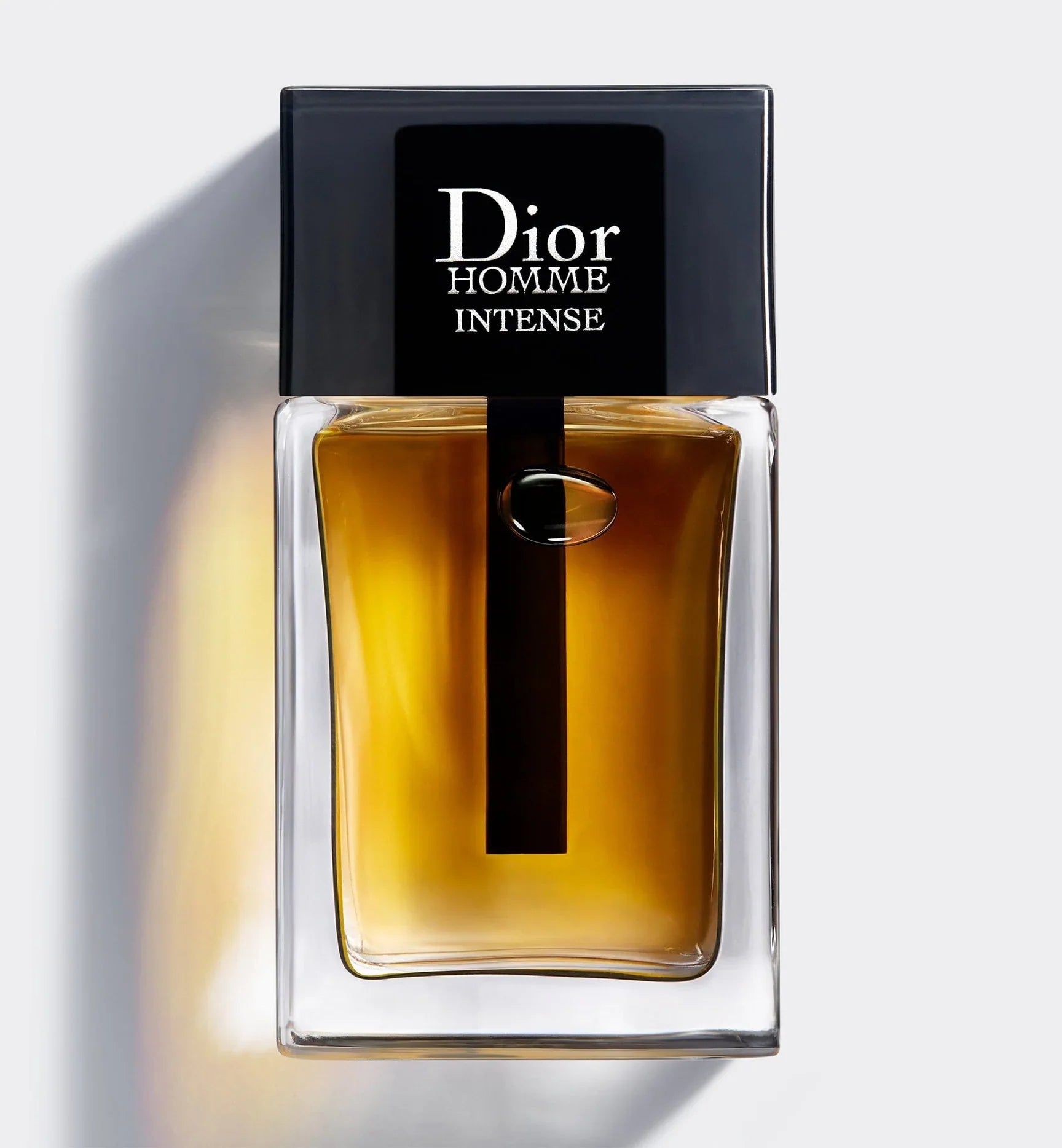 100ml clear architectural Dior Homme Intense bottle with a black cap and amber-colored juice showing a black dip tube.
