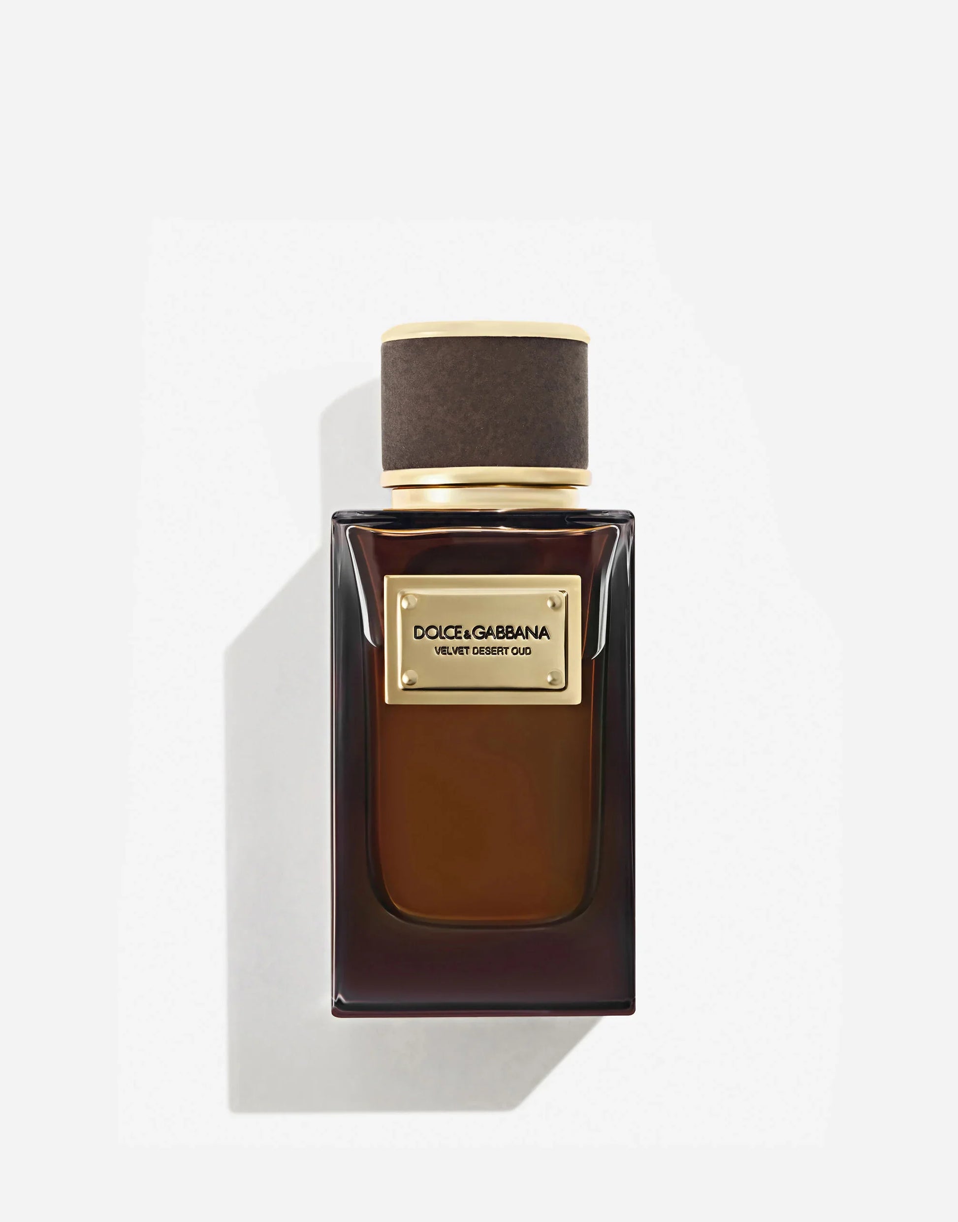 A bottle of Dolce & Gabbana Velvet Desert Oud perfume with a dark liquid visible and a label with gold accents.